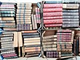 des cartons remplis de vieux livres empilés les uns sur les autres à même le sol