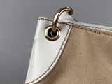 close up of a beige and white purse with a metal handle