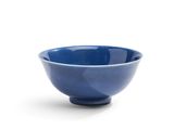 un bol bleu posé sur une surface blanche, sur fond blanc