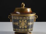 un vase noir et doré muni d'un couvercle, posé sur une table