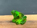a green glass frog sitting on a wooden table
