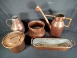 many different types of copper pots and pans on a table