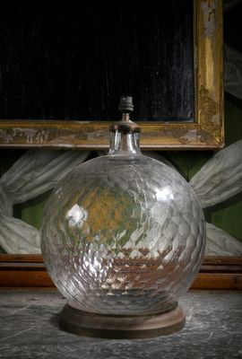 un vase en verre posé sur une table, avec un tableau en arrière-plan