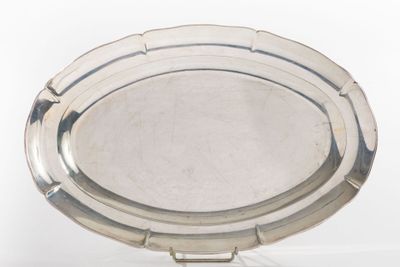 a silver plate on a stand on a white surface