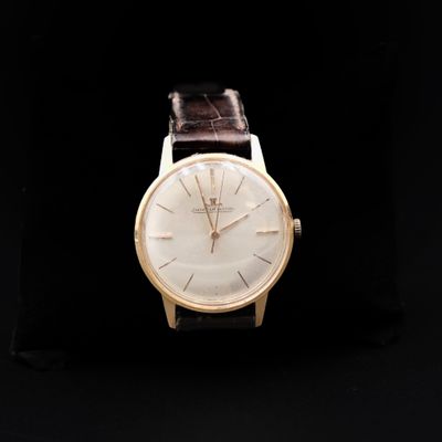 a close up of a watch on a black surface with a black background
