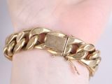 someone is holding a gold bracelet with a chain on it