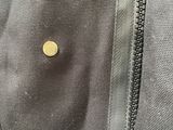 a zipper on a jacket that has a gold button on it
