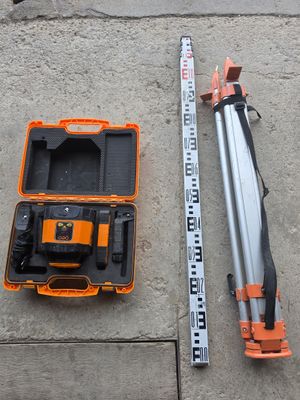 un ensemble d'outils posé sur le sol en béton, à côté d'un mètre ruban
