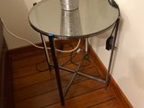 a glass table with a metal vase on top of it