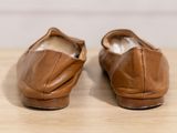 pair of brown leather shoes sitting on top of a wooden table