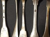 six silver spoons are lined up in a row on a black surface