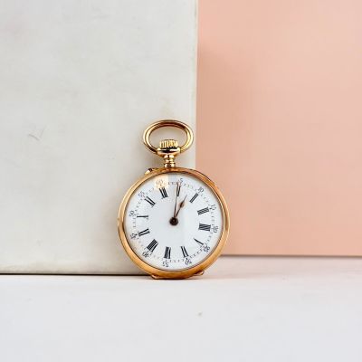 une montre de poche en or posée à côté d'un bloc de marbre