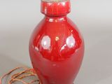 a red vase with a rope around it and a light on top