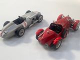 two toy cars sitting next to each other on a white surface