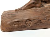 bronze statue of a dog laying on a log with its head resting on the log
