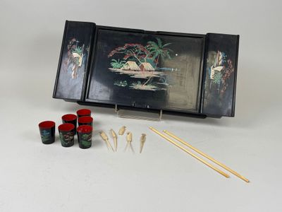 une boîte noire ornée d'une peinture et quatre gobelets rouges