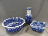 un bol bleu et blanc et deux vases posés sur une table