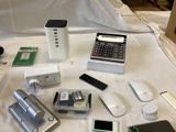 many electronic devices on a bed with a white sheet
