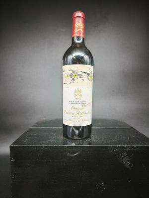une vieille bouteille de vin posée sur une boîte noire