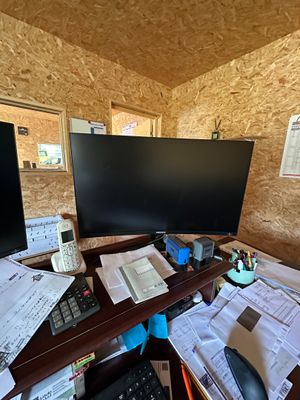 un bureau sur lequel se trouvent deux écrans, un clavier, une souris et des papiers