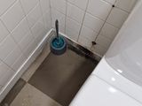 a toilet with a blue brush in the corner of a bathroom