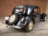 a black car parked in a garage with a brick wall behind it