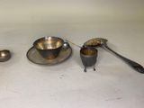 une tasse et une soucoupe en argent, ainsi que des cuillères, posées sur une table