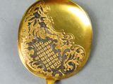a gold spoon with a design on it sitting on a table