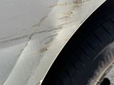 a white car with rust on the side of it