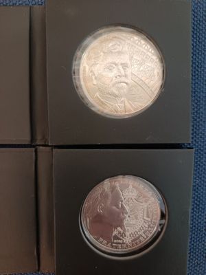 two silver coins are in a black box on a blue cloth