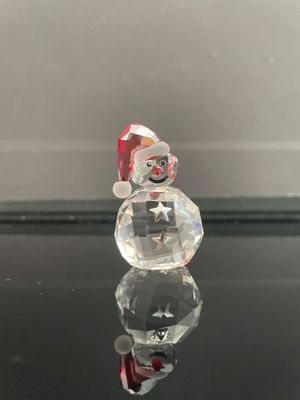 une figurine en verre représentant un bonhomme de neige assis sur une table