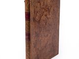an old book sitting on top of a white table next to a white wall