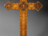 an ornate wooden cross on a stand with a shadow