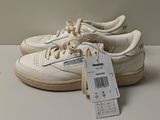 a pair of white sneakers with a price tag on them