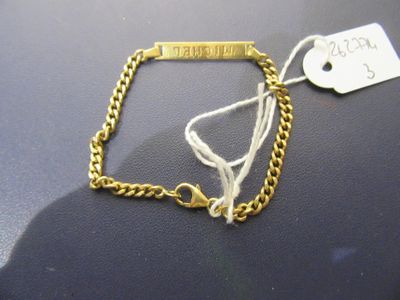 a gold bracelet with a tag on it on a table