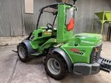un petit tracteur vert garé devant un bâtiment
