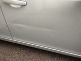 a silver car with a white door handle on the side of the road