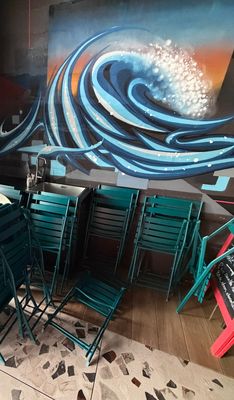des tables et des chaises dans un restaurant où est accrochée une peinture au mur