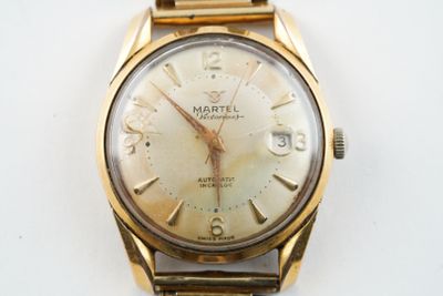 une montre en or avec un cadran blanc sur une surface blanche
