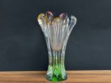 a glass vase on a wooden table with a black background