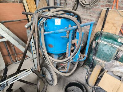 un seau bleu muni d'un tuyau, posé à côté d'un tas d'outils