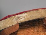 a close up of a red chair with a wooden seat