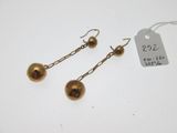 une paire de boucles d'oreilles dorées avec une étiquette attachée