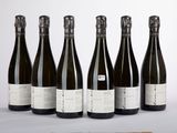 six bouteilles de vin posées sur une table à côté d'une bouteille de vin