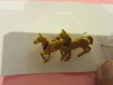 Quelqu'un tient une petite broche en forme de cheval en or posée sur une assiette blanche.