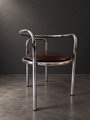 une chaise avec une assise en cuir marron dans une pièce sombre