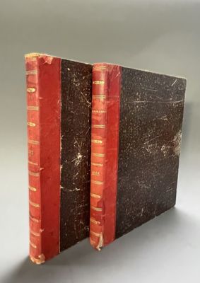 an old book with red bindings sitting on top of a table