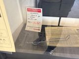 a man taking a picture of a newspaper in a glass case