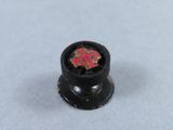 a small black knob with a red cross on it