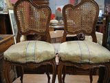pair of antique cane back chairs in a room with a mirror
